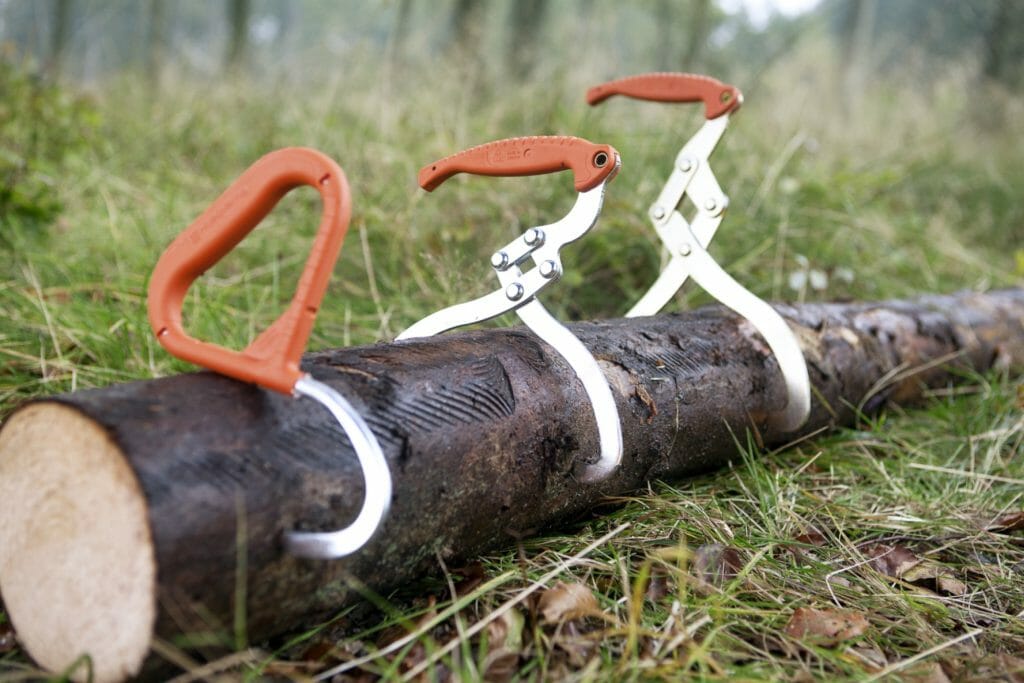A lifting hook and two lifting tongs attached to a log on the ground